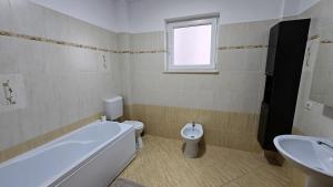 a bathroom with a tub and a toilet and a sink at Rădăuți Residence in Rădăuţi