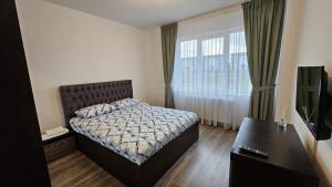 a bedroom with a bed and a desk and a window at Rădăuți Residence in Rădăuţi