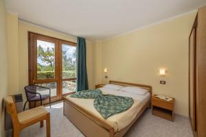 a bedroom with a bed and a window and a chair at Hotel Residence Campi in Tremosine Sul Garda +76 photos