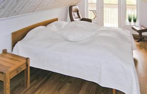 a bed with a white blanket and a chair at Amazing Home In Burseryd With Kitchen in Burseryd
