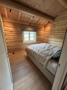 a bedroom with a bed in a wooden wall at Gunhild-stugu in Skogbygd