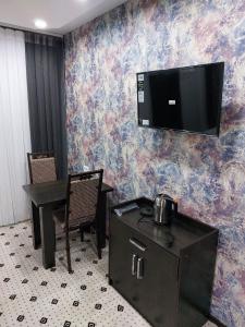 a room with a table and a tv on a wall at Uhum Mountain Guesthouse in Yukary-Ukhum
