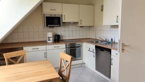 a kitchen with white cabinets and a table and a sink at Nixe in Timmendorf