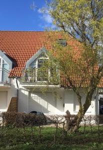 a white house with a red roof and a balcony at Nixe in Timmendorf