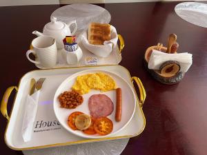 a tray with a breakfast of eggs sausage beans and bread at Swiss Guest Lodge in Boksburg