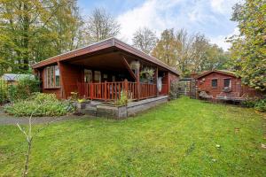 a log cabin with a porch and a yard at Chalet De Drentse Rust in Erm