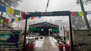 a stage with potted plants and flags in the snow at Nomaden Kasol in Kasol
