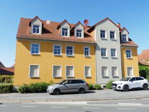 two cars parked in front of a yellow building at Monteurwohnung in Coswig in Coswig