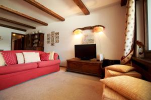 a living room with a red couch and a flat screen tv at Chesa Cuntainta B 4pax - St Moritz in St. Moritz