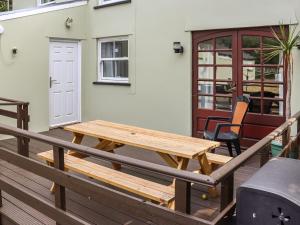a wooden picnic table on the deck of a house at Holly Cottage in Angle