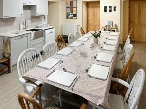 a dining room with a long table with white chairs at Suisnish House in The Braes