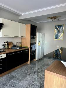 a kitchen with white cabinets and a refrigerator at MAV Beach Villa in Eforie Nord