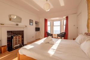 a bedroom with a large white bed and a fireplace at Appleton House - Lower Largo in Lower Largo