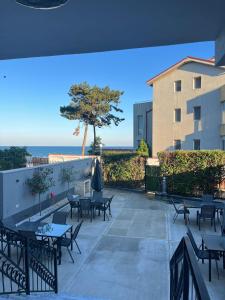a patio with tables and chairs and a view of the ocean at MAV Beach Villa in Eforie Nord