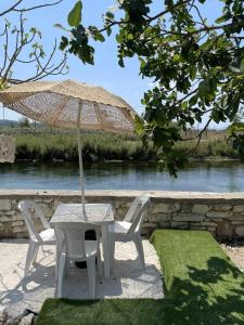 a table and chairs with an umbrella next to a river at Margaret's Guest House in Mesopotam