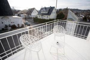 two white chairs and a table on a balcony at JS-Business in Balingen