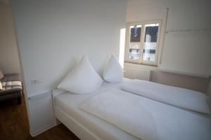 a white bed with white pillows and a window at JS-Business in Balingen