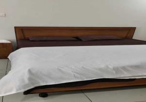 a bed with a wooden frame and white sheets at Kostha Suites in Anumalkudūru +9 photos