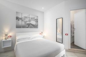 a white bedroom with a bed and a mirror at Excelsior in Piombino