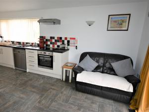 a living room with a couch and a kitchen at Orchard Farm Cottage in Barnby