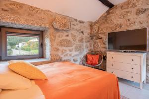 a bedroom with a large bed with an orange blanket at Villa Seara - Casas da Vinha in Celorico de Basto