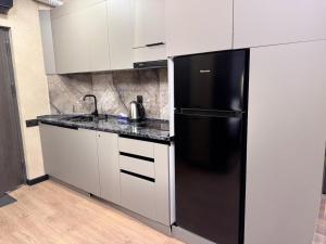 a kitchen with a black refrigerator and white cabinets at Gyumri Moderna in Gyumri