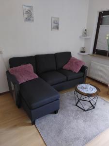 a living room with a black couch and a table at Ferienwohnung im Ohmtal in Homberg an der Ohm