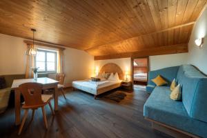 a living room with a blue couch and a bed at Garni Tschutscherhof in Laion +73 photos