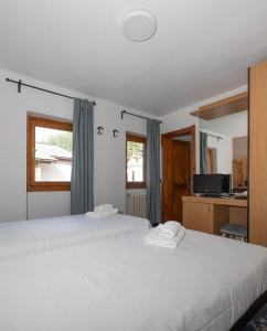 two beds in a room with two white beds at Smart Hotel Renzi in Folgarida
