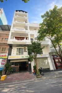 a tall white building with a tree in front of it at Anh Đào 2 Hotel in Hai Phong +29 photos