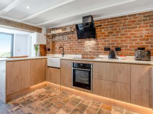 a kitchen with wooden cabinets and a brick wall at Ty Gladys in St. Davids