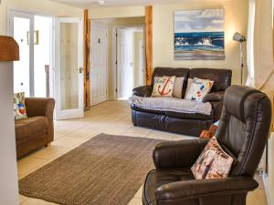 a living room with a leather couch and chairs at The Seas Beach House in Bacton