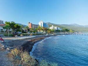 a beach with chairs and buildings and the water at Çidihan HOTEL in Kuşadası