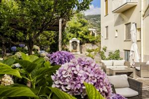 a garden with purple flowers in front of a building at Sisters Hotel in Piano di Sorrento