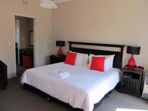 a bedroom with a large white bed with red pillows at Melody Guest House in Centurion +13 photos