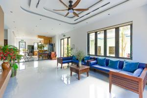a living room with a blue couch and a ceiling at Cocohamlet Villa in Thanh Ðông (1)