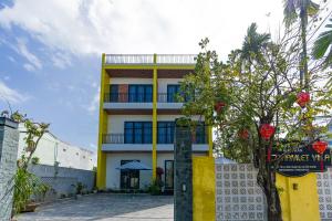 a yellow and white building with a tree in front of it at Cocohamlet Villa in Thanh Ðông (1)