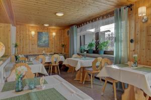 a restaurant with white tables and chairs and wooden walls at Hotel Haus Anna in Bayerisch Eisenstein