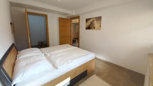 a bedroom with a bed with white sheets at Luxus Terrassenappartement Berg & See 1 in Bodensdorf +28 photos