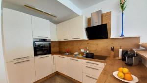 a kitchen with white cabinets and a plate of fruit at Luxus Terrassenappartement Berg & See 1 in Bodensdorf