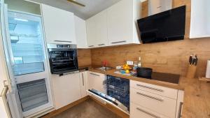 a kitchen with white cabinets and a stove top oven at Luxus Terrassenappartement Berg & See 1 in Bodensdorf