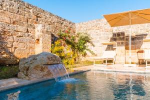 a swimming pool with a waterfall in a stone wall at Masseria Lovetere Rooms - Salento Selection in Copertino