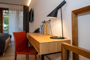 ein Schreibtisch mit einer Lampe und einem roten Stuhl in einem Zimmer in der Unterkunft LILIENBERG in Ermatingen