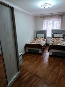 two beds in a room with wooden floors and a window at Jermuk Calm House in Jermuk