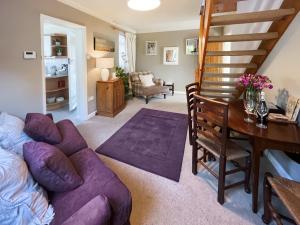 a living room with a purple couch and a desk at Lavender Cottage in Louth