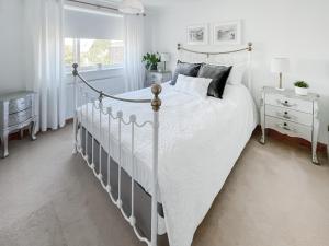 a white bedroom with a white bed and a window at Lavender Cottage in Louth