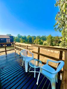 two chairs and a table on a wooden deck at Tiny House Pangal in Pichilemu