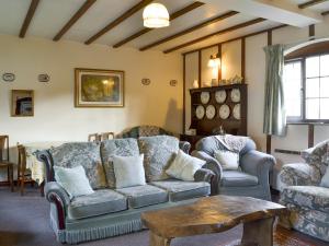 a living room with a couch and chairs and a table at Grove Sprightly Barn in Craven Arms