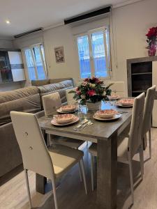 a dining room table and chairs with plates and flowers at Living Canovas in Alcalá de Henares +8 photos