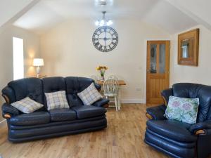 a living room with a couch and a clock on the wall at Penrhos Bach in Llanerchymedd